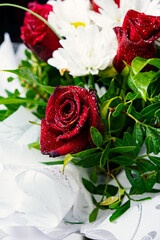 Bouquet of flowers bright red roses and white daisies, macro photo floristry, shop advertising and flower delivery bouquets, rosebud with drops of dew water freshness