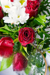 Bouquet of flowers bright red roses and white daisies, macro photo floristry, shop advertising and flower delivery bouquets, rosebud with drops of dew water freshness, mirror reflection of flowers