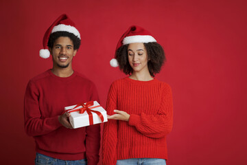 Winter holidays celebration. Young african american smiling man offering Christmas gift