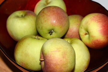 Closeup on green and red fresh tasty apples in a red bowl