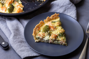 Quiche (open pie) with trout, broccoli and cheese. Homemade unsweetened pastries, traditional pie. Close-up.