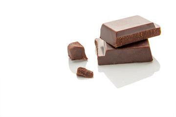 Pieces of natural dark chocolate on a white background. Copy space