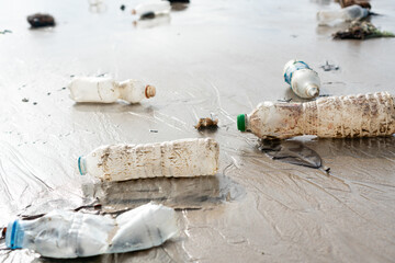 Plastic bottles and other trash abandoned on the beach. Environmental pollution, Ecological problem concept. Close up