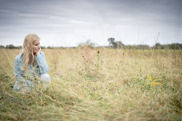 Young Woman In Long Grass In A Field Looking Away