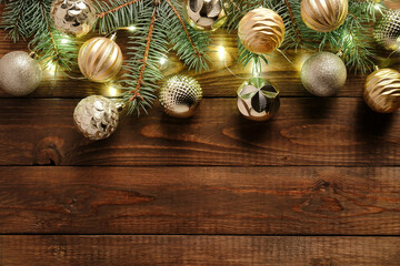 Obraz na płótnie Canvas Christmas balls decoration in vintage style and fir tree branches with lights on old wooden background. Flat lay, top view. Christmas greeting card template, postcard design, banner mockup