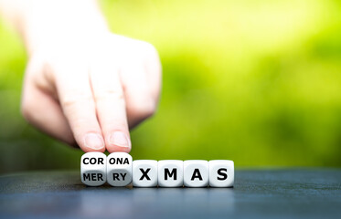 Symbol for a corona influenced Christmas. Hand turns dice and changes the expression "merry xmas" to "corona xmas".