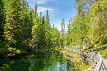 View of The Pyha-Luosto National Park in summer, stones, trees, wooden walkway and natural pond, Lapland, Finland