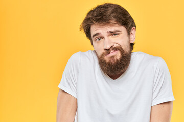 Obraz premium Bearded man in a white T-shirt gestures with his hands emotions studio yellow background