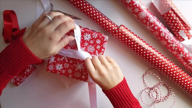 Woman ties a ribbon bow and wrapping presents