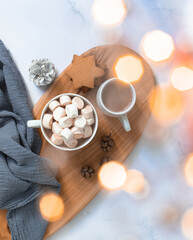 Winter breakfast with cookies, hot chocolate, cocoa drink with marshmallows, served on a wooden board and a marble table with festive Christmas decorations