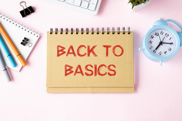 Business concept. Notepad with text BACK TO BASIC notepad, keyboard, alarm clock, markers, notepad, on a pink background