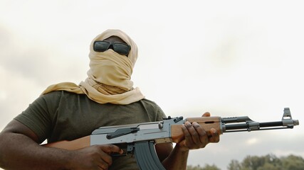 Concept of terrorism. Rebel soldier aiming at targets with an AK-47 machine gun. Close up. High...