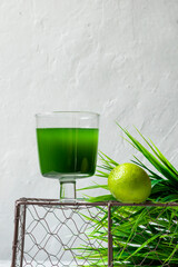 Chlorella detox healthy drink in glass with lime on an openwork podium on a light background....