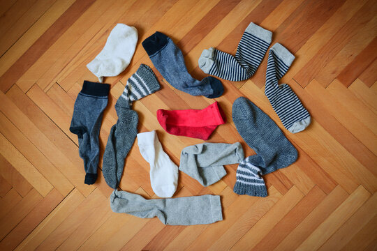 Pile Of Socks. Missing Red Sock. Search For The Missing Sock. Socks On Wooden Floor. Pairs Of Socks But One Is Missing.