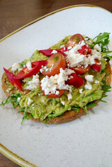 Smashed avocado on toast with red chillis, tomatoes and feta cheese - portrait