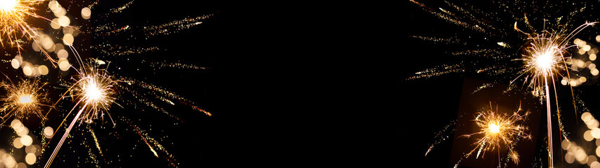 2025 Silvester / New Year background banner panorama - sparklers firework and bokeh lights on black...