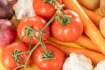 Close up of tomatoes and carrots on a yellow wooden kitchen table