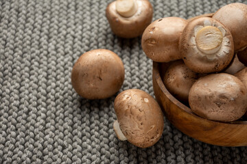 Top view of portobello mushrooms in wooden bowl, on gray knitted blanket, horizontal, with copy space