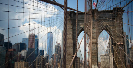 Brooklyn Bridge with modern buildings on the other side of the steel mesh.