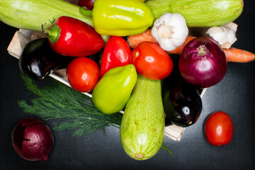 Gifts of autumn. Composition with vegetables in a wooden box on a black table.