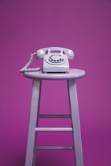 old telephone, retro rotary dial phone with numbers for calling, purple on stool, vintage