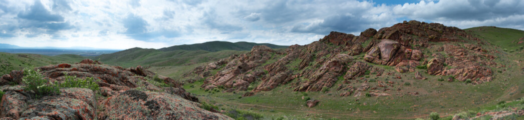 Red stone rocks and hills with bizarre shapes. Panoramic image. Spring. Almaty region, Kazakhstan.