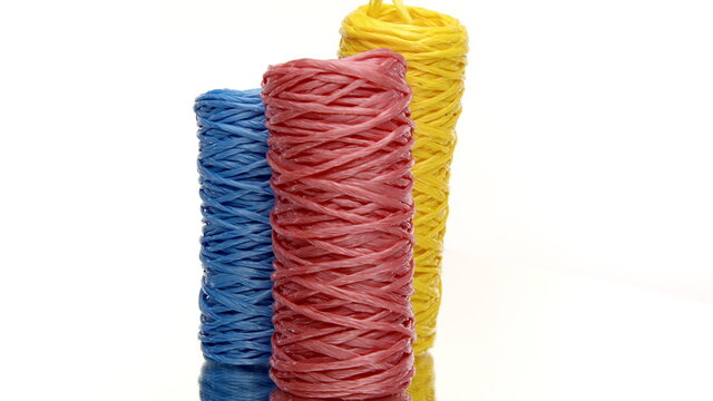 Three skeins of colorful recycled plastic twine rotating on isolated white background. Hank of nylon rope knot strings in motion. Eco-friendly materials, ecology concept. Copy space - Powered by Adobe