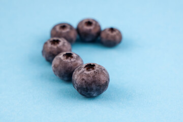 Blueberries forming a half heart shape on light blue background