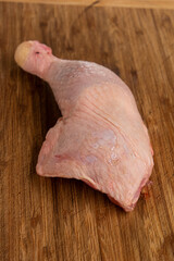 Raw chicken leg whole on wooden kitchen board top view