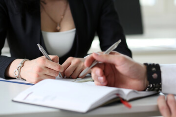 Group of people hold silver pen ready to make note in opened notebook sheet closeup. Training...