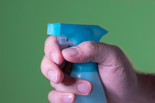 Light Blue Water Sprayer Bottle Nozzle Held In Caucasian Male Hand Close Up Shot Isolated On Green