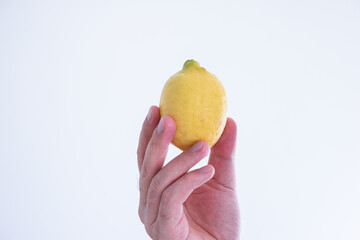 Whole yellow lemon held by Caucasian male hand close up shot isolated on white