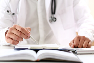 Doctor hand hold silver pen filling patient history list at clipboard pad closeup. Physical, exam, er, disease prevention, ward round, visit check, 911, prescribe remedy, healthy lifestyle concept