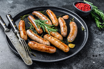 Grilled sausages with rosemary herbs, beef and pork meat. Black background. Top view