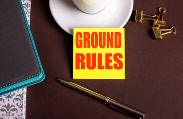 GROUND RULES is written in red on a yellow sticker on a brown background next to multi-colored paper clips.