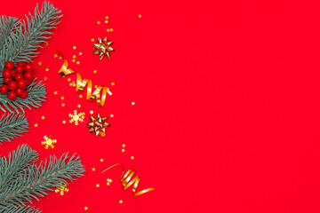 Fir tree branches and sparkling decorations on bright red background with copy space for your text. Christmas and New Year concept.