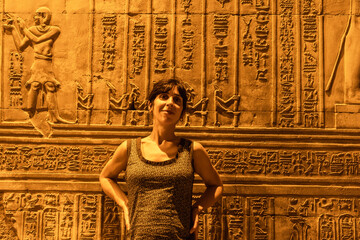 A young woman looking at Egyptian drawings and hieroglyphs at the Temple of Kom Ombo, the temple dedicated to the gods Sobek and Horus. In the town of Kom Ombo near Aswer, Egypt.