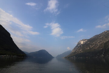 Clear water in Italy over a mountain range with still lake in foreground during the daytime in the late summer