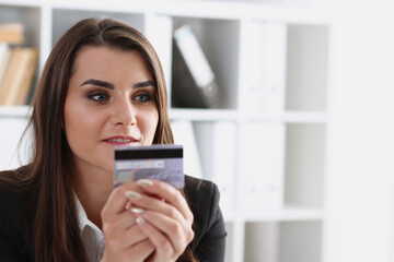 Business woman in the office holds a plastic credit debit card in her hand makes online purchases content commerce on the Internet shop ecommerce