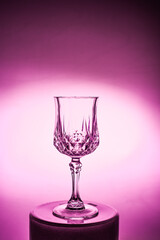 Wineglass on the light background. Fine cristal glassware concept. Vertical, toned in pink