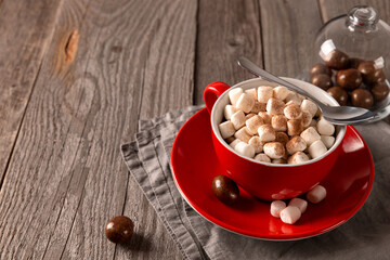Hot chocolate with marshmallow in red cup on wooden table
