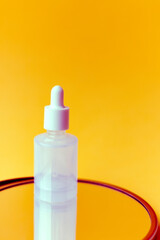 Skincare serum pipette bottle on a yellow background with a reflection. Closed. Closeup view