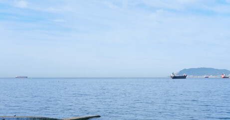 sea bay view. ships on a horizon. calm and peaceful sea. copy space for text. cloudy weather.