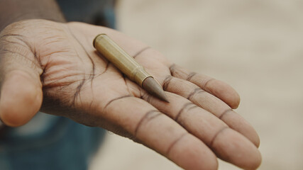 Close up, black man with mask over face holding rifle bullet. High quality photo