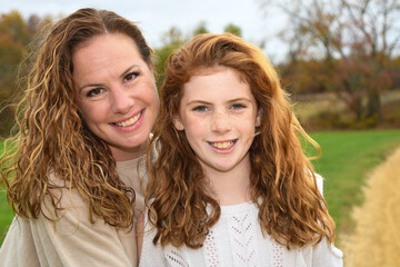 Mother and daughter pose for autumn portrait. 