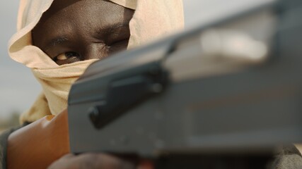 Obraz premium Concept of terrorism. Rebel soldier aiming at targets with an AK-47 machine gun. Close up. High quality photo