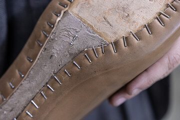 Brown leather cardavan was pulled over a shoe last and the leather was fixed with nails, one of the stages of creating handmade shoes