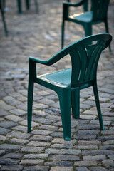 Green plastic chairs on cobblestone maintaining the social distance imposed by corona virus restrictions prior to an event