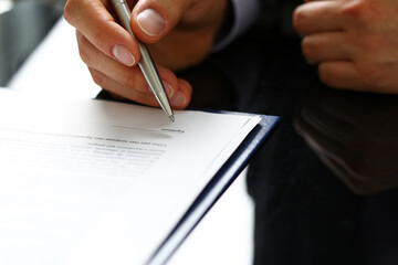Naklejka premium Male arm in suit and tie fill form clipped to pad with silver pen closeup. Sign gesture, read pact, sale agent, bank job, make note, loan credit mortgage investment, finance chief, legal law concept