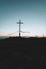Obraz premium Gipfelkreuz am Riedberger Horn während dem Sonnenuntergang oder der blauen Stunde